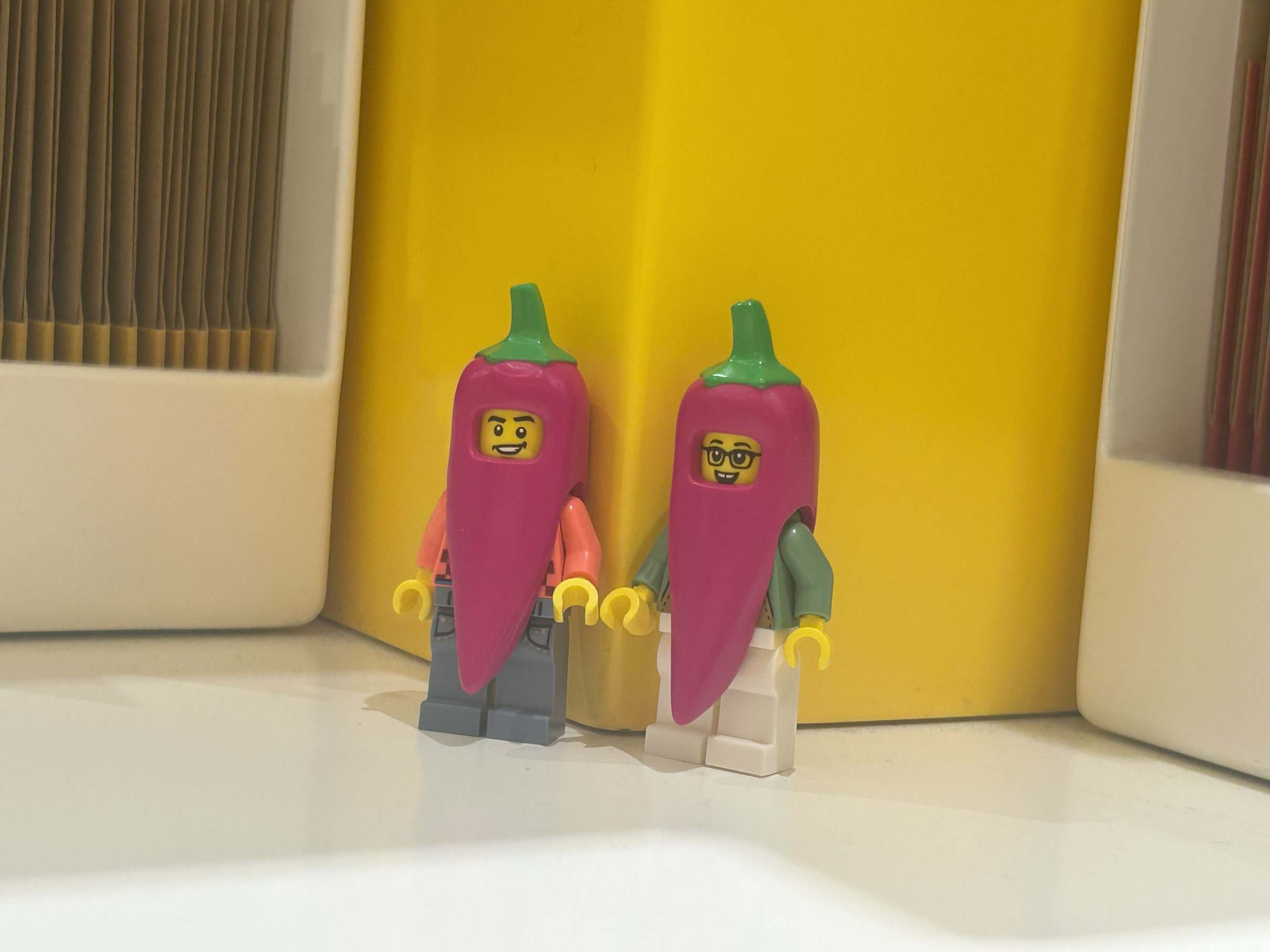 Image of two LEGO minifigures wearing purple chili suites. They are smiling and standing next to each other.